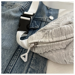 Detailed close-up of white embossed jacquard texture and durable buckle on crossbody bag