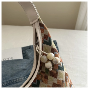 Close-up of geometric jacquard tote with ivory leather trim and marble bead zipper pull