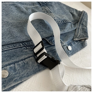 Detail of white nylon strap with black plastic buckle over a denim jacket close-up