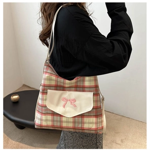 Detail view of vintage plaid shoulder bag featuring an embroidered pink bow on the front pocket