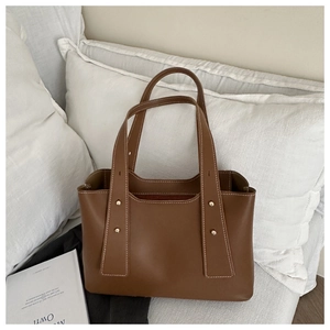 Detail of brown tote bag with gold rivets, white contrast stitching and smooth leather finish