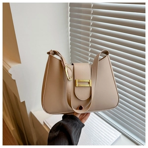 Detail view of beige crescent baguette bag featuring gold buckle and smooth PU leather