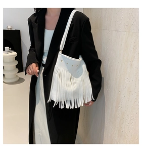 Detailed view of white leather shoulder bag featuring long fringe and metallic stud accents