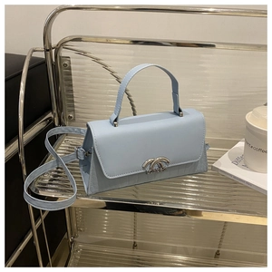Detail view of a sky blue leather handbag with crocodile pattern and silver metal buckle