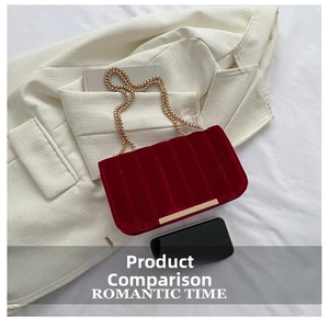 Detail of red velvet crossbody bag with vertical quilting and gold chain strap
