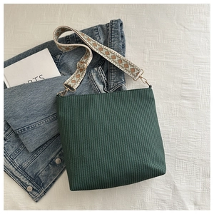 Detail of dark green woven bucket bag with adjustable bohemian jacquard shoulder strap