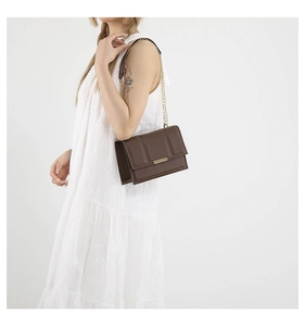 Detail of coffee brown quilted leather bag with elegant gold chain strap and metal clasp