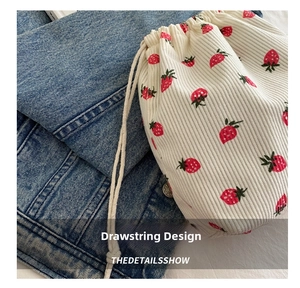 Detailed texture of white corduroy drawstring bag with vibrant red strawberry print pattern