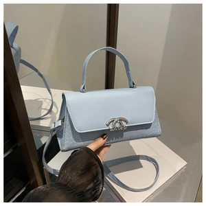 Detail of sky blue crossbody bag featuring mock crocodile texture and silver lock
