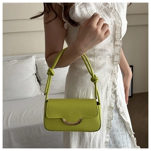 Détail du sac à main en cuir vert citron avec boucle dorée et bandoulière à nœuds chic