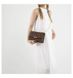Close-up of a dark brown quilted crossbody bag with elegant gold chain shoulder strap