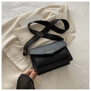 Detail of minimalist black crossbody bag with adjustable wide strap and gold hardware