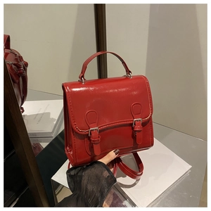 Close-up of glossy red fashion backpack with silver buckles and decorative straps