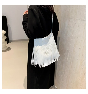 Detail view of a white fringe shoulder bag with gold studs and a bohemian aesthetic
