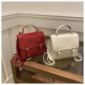 Detail of vintage double-buckle bags in glossy red and matte beige leather textures