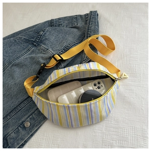 Détail du sac banane en toile rayée montrant la capacité intérieure avec accessoires