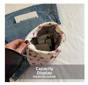Detail of strawberry print corduroy bucket bag showing sunglasses and wallet storage