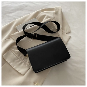Minimalist black leather square bag detail with adjustable wide nylon shoulder strap