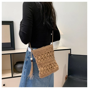 Detail of bohemian straw bag featuring intricate crochet patterns and long stylish tassels