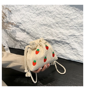 Detailed texture of straw woven bucket bag featuring cute 3D strawberry embroidery