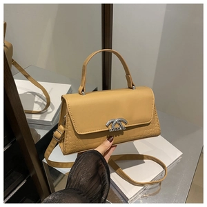 Detail of tan crossbody bag showing smooth leather and crocodile texture with silver logo