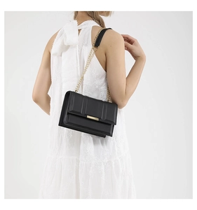 Close-up of a black leather shoulder bag with gold hardware and chain strap on a model