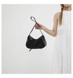 Détail d'un sac porté épaule en cuir PU noir avec un grand nœud décoratif et zip métallique