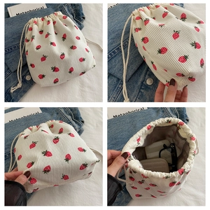 Detail of white corduroy drawstring bucket bag with red strawberry print and interior lining