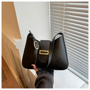 Close-up of black leather baguette bag with metal buckle and adjustable shoulder strap