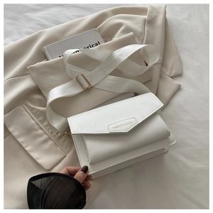 Detail of white square crossbody bag with wide nylon strap on beige blazer