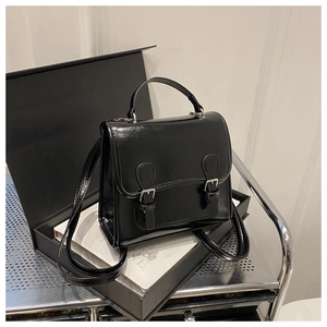 Close-up of a glossy black multi-way backpack featuring silver buckles and a top handle