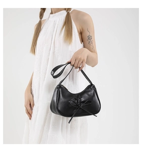 Détail du sac demi-lune plissé noir avec un nœud décoratif et une texture en cuir lisse