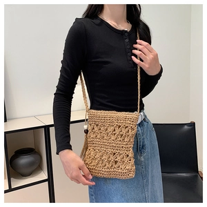 Detail of woven straw crossbody bag with side wooden beads and fringe tassels decoration