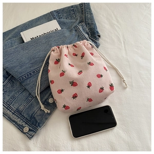 Détail du sac à cordon en velours rose avec imprimé fraises sur fond lifestyle