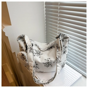 Détail du sac cabas en velours côtelé blanc cassé avec imprimé floral et breloque ronde