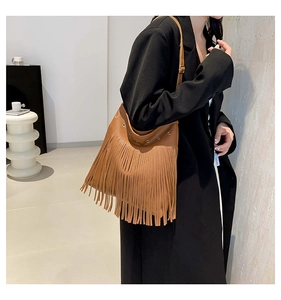 Close-up of brown fringe shoulder bag with pebble texture and metallic eyelets details