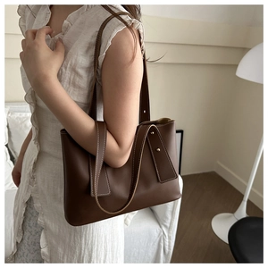 Detailed view of deep brown leather tote bag with white contrast stitching and metal hardware