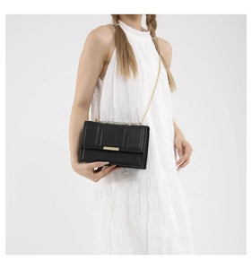 Detail of black glossy leather bag with vertical ribbing and golden chain strap
