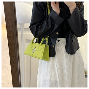 Détail du petit sac bandoulière carré vert fluo avec étoile argentée porté par un modèle