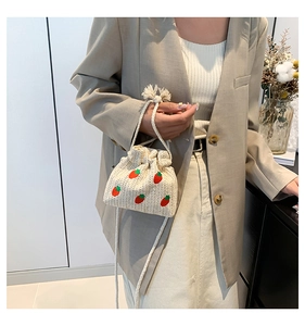 Detailed strawberry embroidery on a beige woven straw bucket bag with cotton rope handles