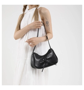 Détail du sac sous le bras en similicuir noir en forme de croissant avec un nœud chic