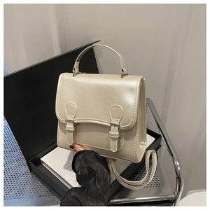 Detail view of the cream white PU leather crossbody bag with top handle and buckle straps