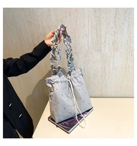 Detail of grey polka dot tote bag featuring ruffled handle and drawstring closure