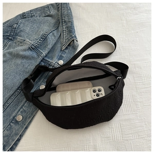Detail view of black textured waist bag capacity with phone and wallet inside