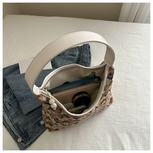 Interior detail of large woven tote bag showing daily items like tablet and umbrella