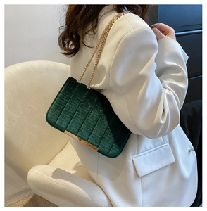 Detail of dark green velvet shoulder bag with pleated texture and gold chain strap
