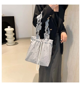 Detail of light blue ruffle tote bag with pearl accents and decorative drawstring texture