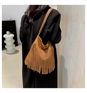 Close-up of brown pebbled leather shoulder bag with long flowing bohemian tassels