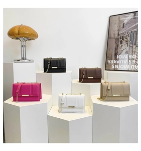 Collection of chain strap baguette bags in five colors on geometric display stands