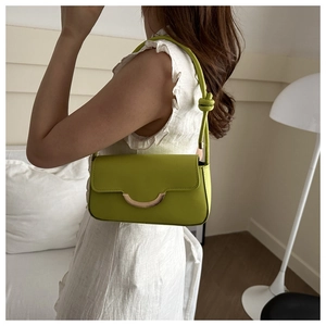 Close-up of lime green baguette bag featuring golden buckle and knotted shoulder strap detail